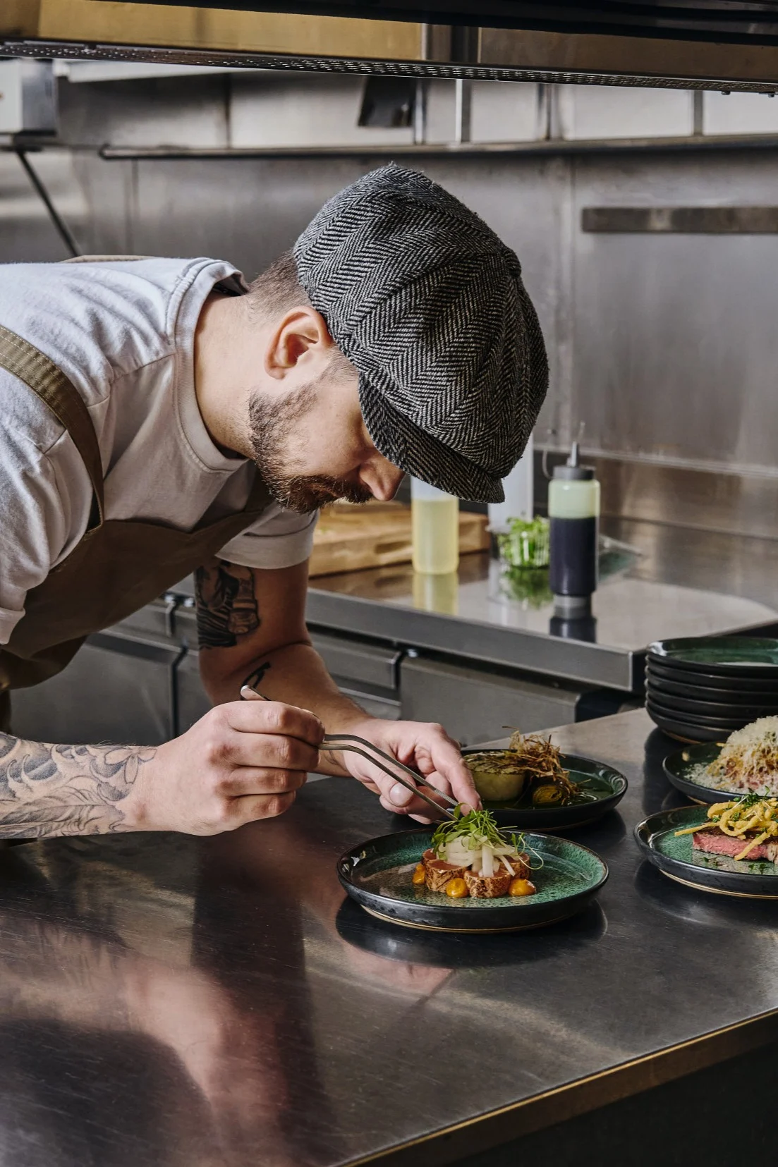 En profesjonell kokk legger på garnityr med en pinsett – riktig verktøy gjør det enkelt å anrette mat som en proff.
