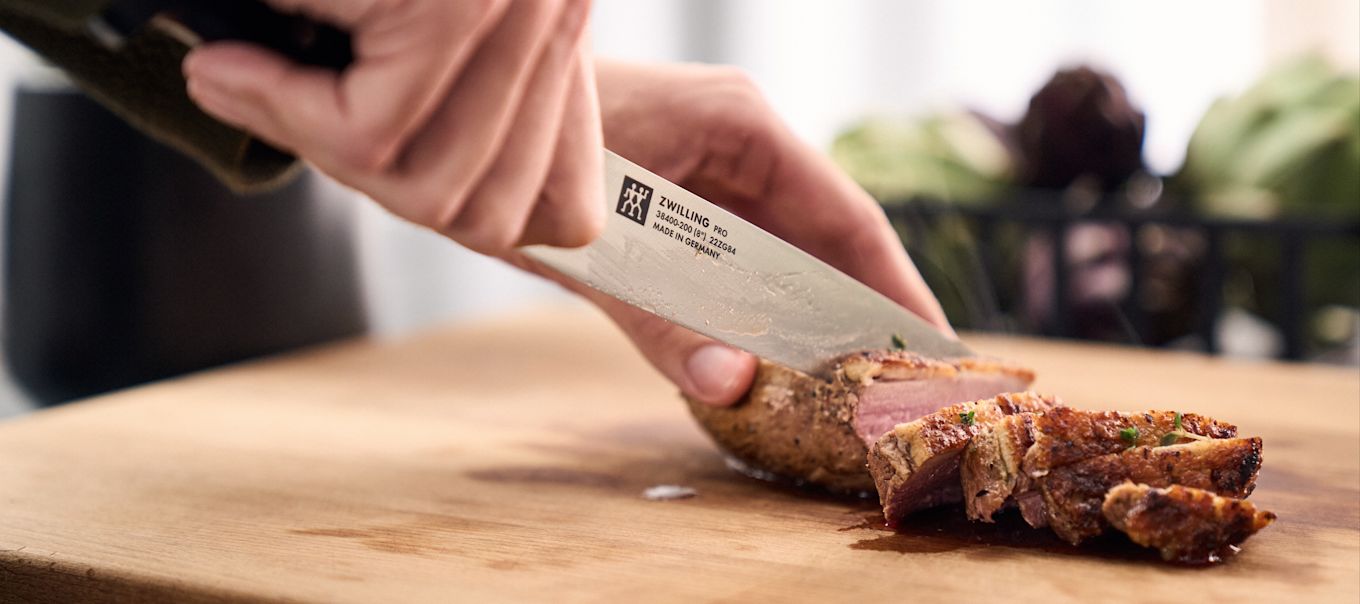 En kniv skjærer gjennom en stekt svinefilet.
