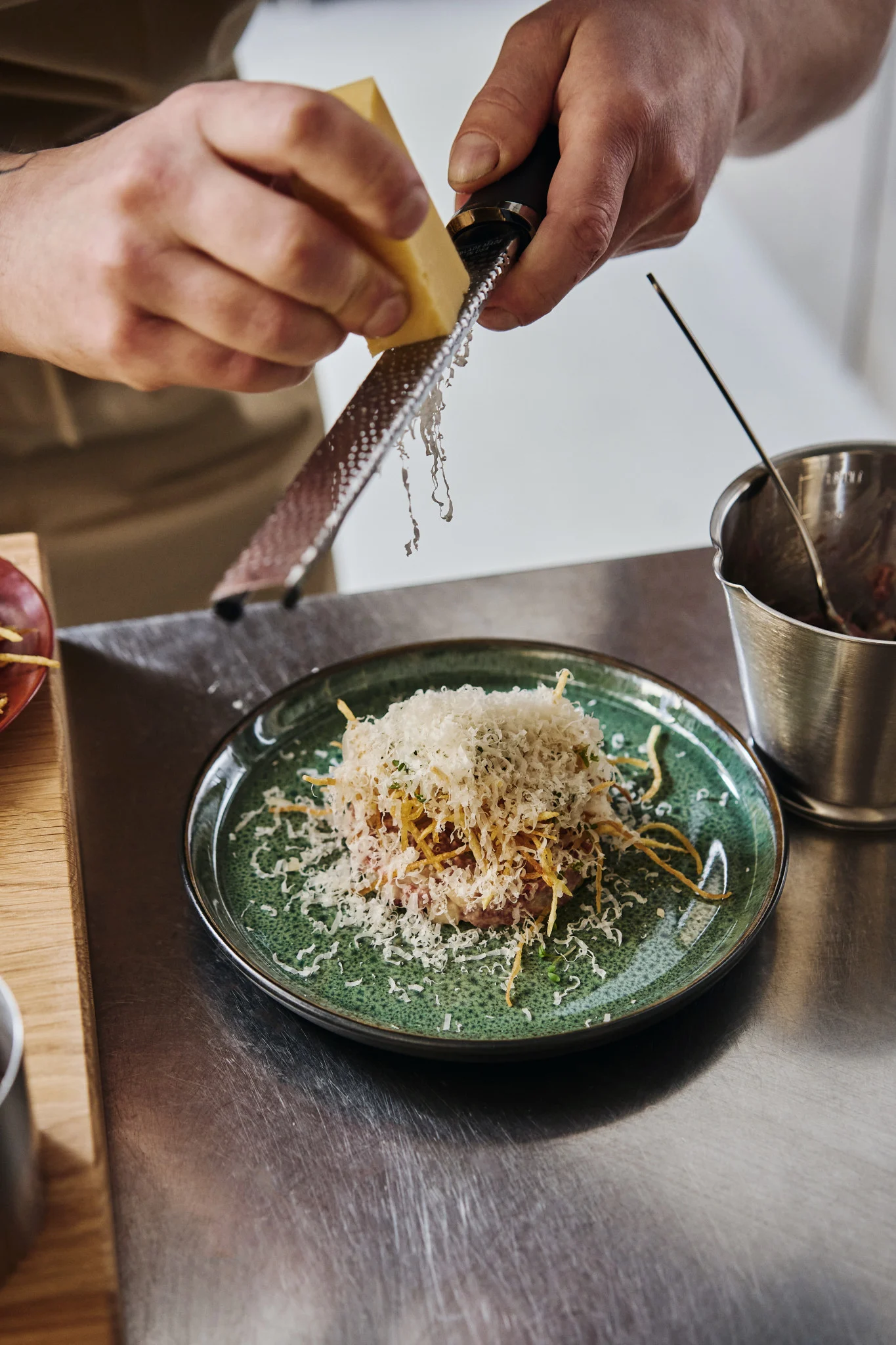 Her får du inspirasjon til å anrette som en profesjonell – en kokk river ost over en grønn tallerken og setter prikken over i-en på retten.
