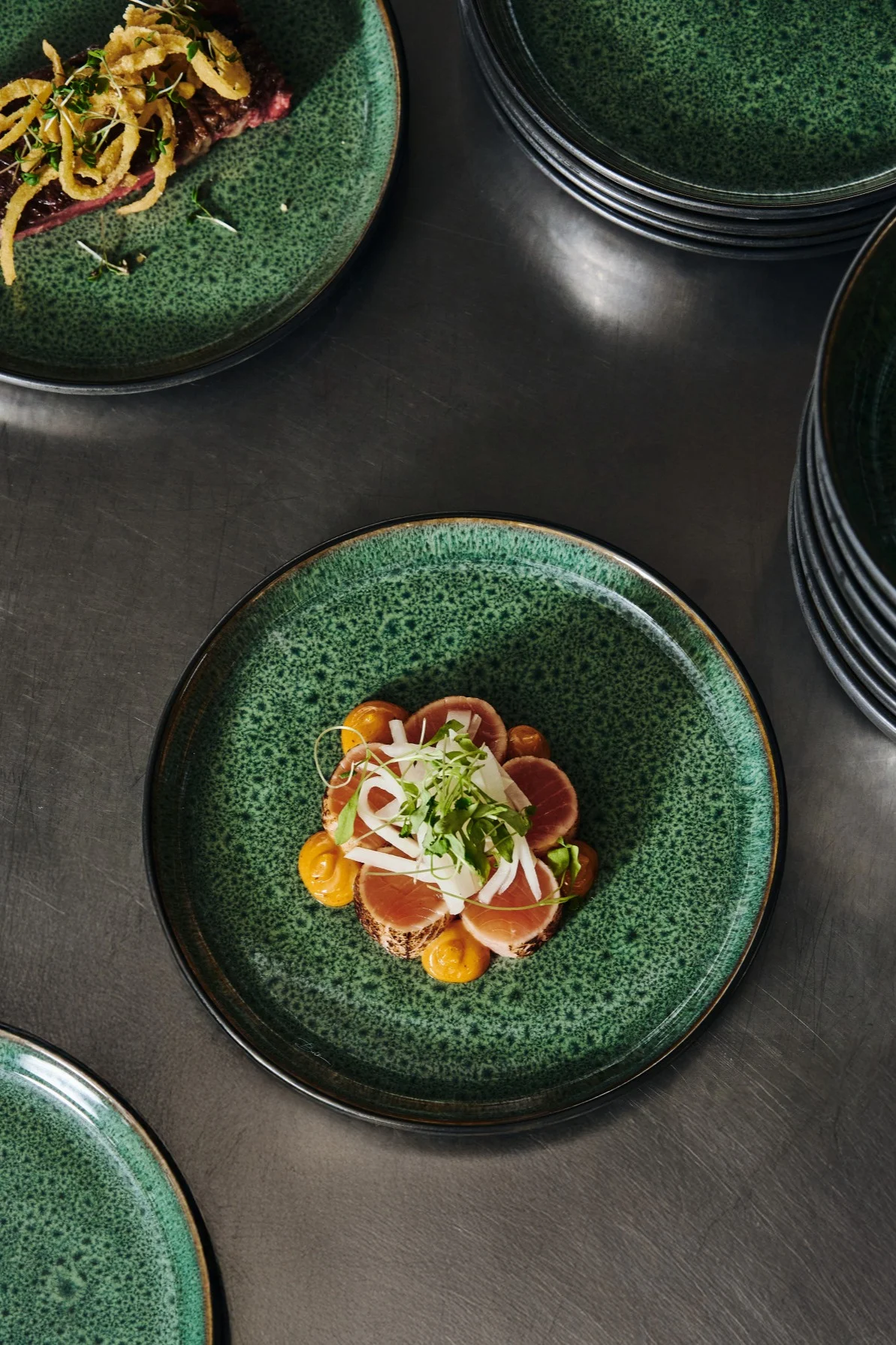 Å anrette mat i oddetall, som du ser her, er et enkelt grep for å legge opp mat som en profesjonell. Her ser du en tallerken med oransje laks på en grønn tallerken fra Bitz – en fargekombinasjon som får maten til å virkelig skinne.